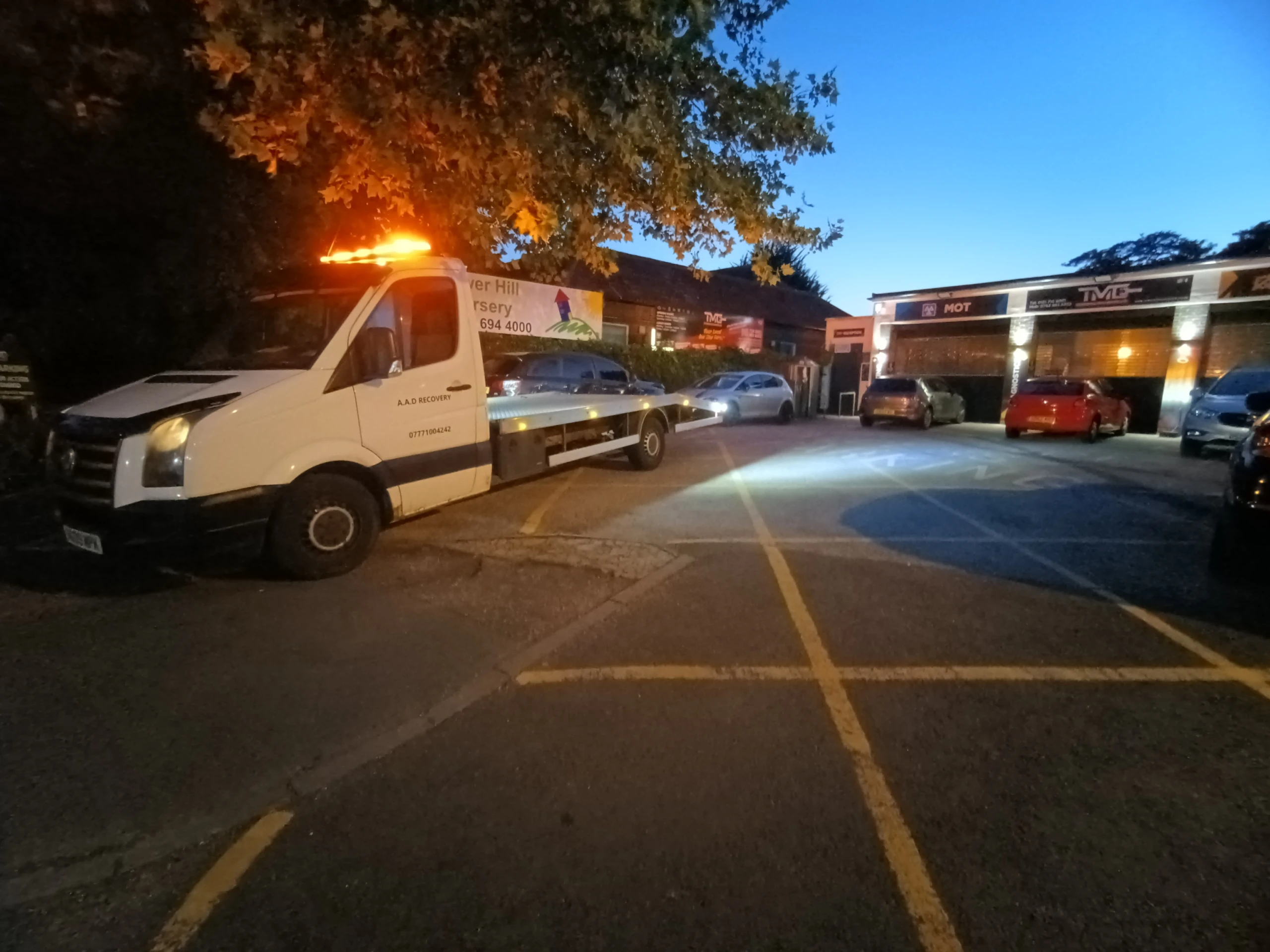 AAD recovery truck with beacons attending a roadside breakdown at dusk